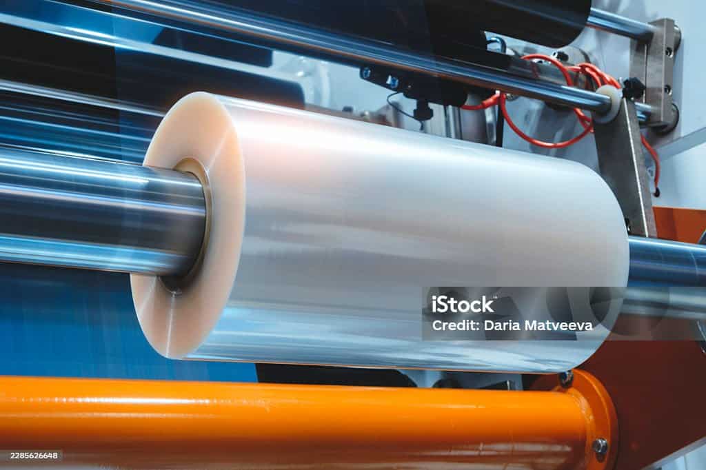 Automatic polyethylene plastic bag production machine with lighting effect. Close-up  roller of the plastic bag production machine in  light blue scene. product packaging concept
